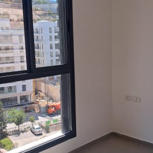 קיר לבן עם חלון גדול וצל על הרצפה