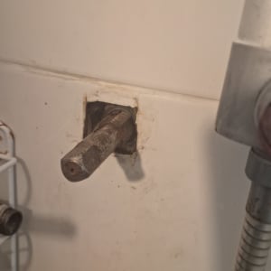 צינור מתכת בולט מהקיר עם חיבורי אינסטלציה