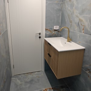 חדר אמבטיה עם כיור וברז זהב על רקע קיר שיש אפור