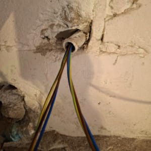 חוטי חשמל צבעוניים יוצאים מקיר בטיח שבור