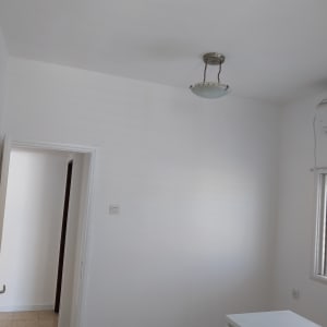 קירות צבועים בלבן בחדר עם מנורה