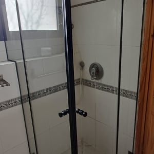 מקלחון זכוכית עם דלתות שחורות בחדר אמבטיה