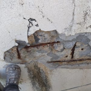 קיר עם סדקים וחלודה, נעליים מלוכלכות