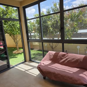 מרפסת סגורה עם חלונות גדולים ועצים בחוץ