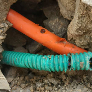 צינורות כתומים וירוקים בתוך קיר שבור