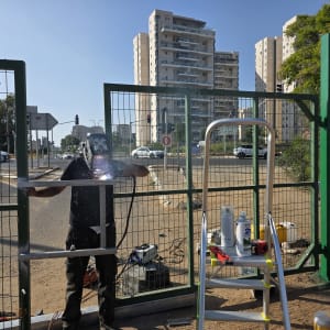 ריתוך שער מתכת ירוק ברחוב עם בניינים ברקע