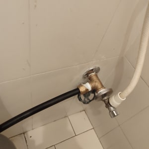 צינור שחור מחובר לברז מתכת על קיר