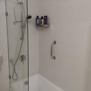 מקלחת עם ראש מקלחת, מדף עם בקבוקים, ידית אחיזה