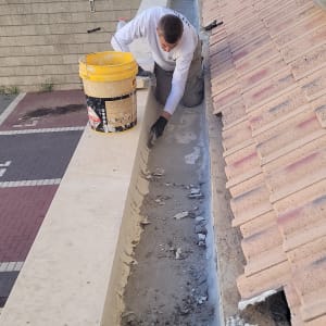 אדם מתקן תעלת ניקוז על גג רעפים