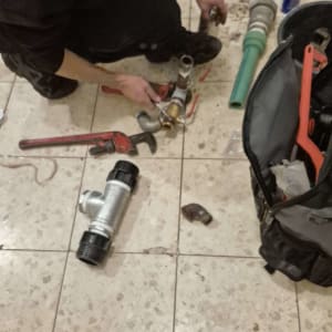 אדם עובד על צנרת עם כלים על רצפה