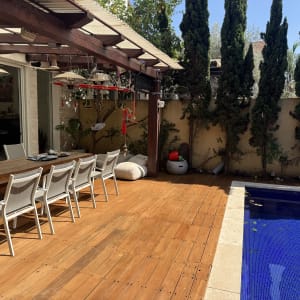 פינת ישיבה עם שולחן עץ ובריכה בגינה