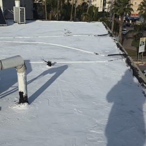 גג אטום עם חומר איטום לבן, צינור וצל של אדם