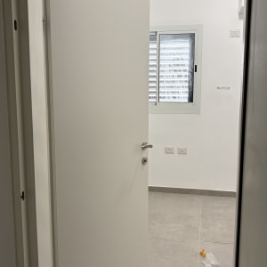 דלת פנים לבנה ומודרנית מותקנת בפתח חדר מגורים