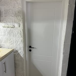 דלת לבנה עם ידית שחורה בקיר לבנים