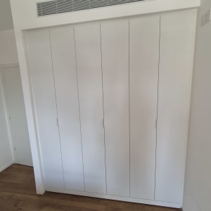 ארון בגדים לבן עם דלתות עץ על רצפת עץ