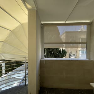 סוכך בד מתוח על מרפסת עם מעקה מתכת