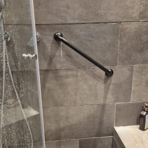 מקלחת עם מוט אחיזה על קיר אריחים אפורים