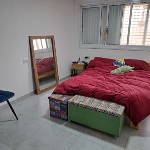 חדר שינה מסודר עם מיטה, כיסא ומראה