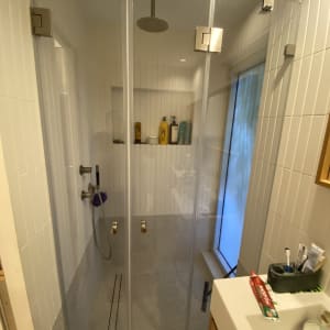מקלחון חזית מזכוכית שקופה המותקן מקיר לקיר בחדר רחצה