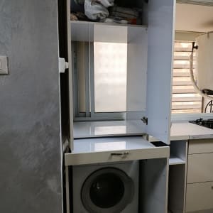 מכונת כביסה בתוך ארון במטבח עם מדפים פתוחים