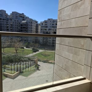 מעקה זכוכית עם נוף לבניינים וגינה