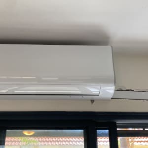 מזגן קיר לבן מותקן על קיר עם צינור חשוף