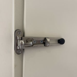 בריח מתכת על דלת לבנה עם ברגים