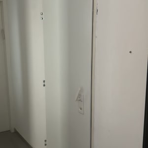 דלת לבנה עם ידית וכמה צירים על הקיר