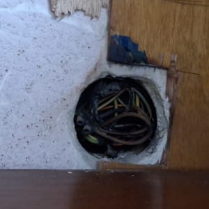 חוטי חשמל חשופים בקיר עם חור עגול