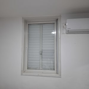 חלון עם תריסים סגורים וקיר לבן