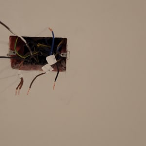 חוטי חשמל חשופים בקופסת חיבורים בקיר