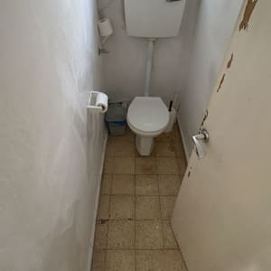 שירותים עם קירות מתקלפים ורצפה מרוצפת