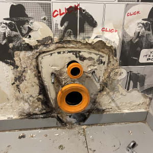 צינור כתום בקיר עם כלי עבודה על הרצפה