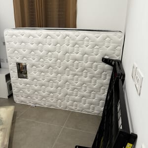 מזרן עומד על הקיר ליד מסגרת מתכת שחורה