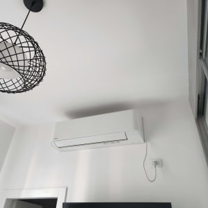 מזגן לבן מותקן על קיר עם כבל חשמל
