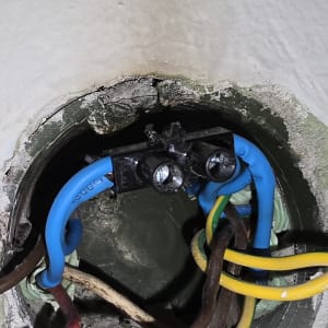 חוטי חשמל צבעוניים מחוברים לקופסת חיבורים בקיר