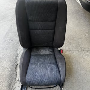 מושב רכב שחור על רצפת בטון ליד רכב