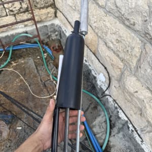 כלי עבודה חשמלי מוחזק ביד על רקע קיר אבן