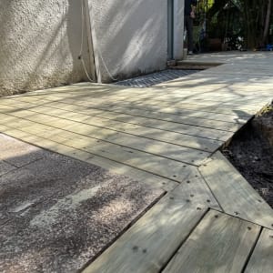 דק עץ מותקן בחצר עם צמחייה מסביב