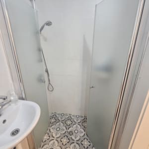 מקלחת עם דלתות זכוכית ורצפת אריחים מעוצבת
