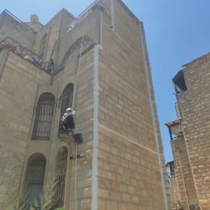 אדם מטפס על קיר אבן עם ציוד איטום