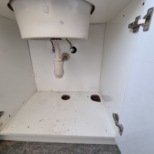 ארון מטבח פתוח עם כיור וצנרת מתחתיו