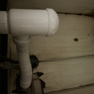 צינור פלסטיק לבן מתחת לכיור עם חיבורי הברגה