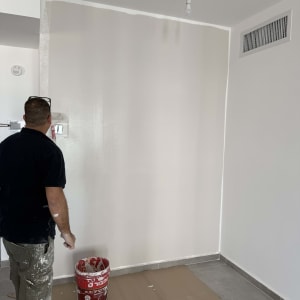 אדם צובע קיר עם דלי צבע אדום