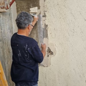 אדם מורח טיח על קיר עם שפכטל