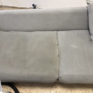 ספה אפורה עם כתמים, שואב אבק בתחתית התמונה