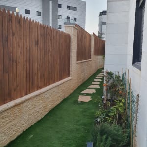 גינה עם דשא סינתטי וגדר עץ