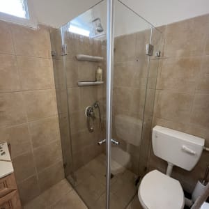 מקלחון זכוכית עם מדפים ומקלחת יד