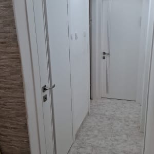 דלתות לבנות במסדרון עם רצפת קרמיקה