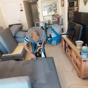 אדם מנקה ספה עם מכונת ניקוי מקצועית